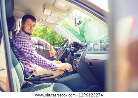A picture of a beautiful young happy businessman smiling at the camera, sitting behind the wheel of a car. travel comfort transportation safety