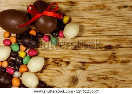 Easter composition with chocolate eggs on wooden background. Top view, copy space