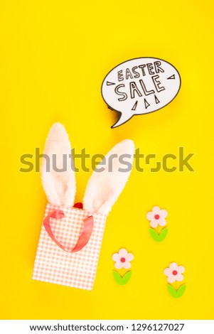 Creative Top view flat lay holiday promo composition Easter sale bunny ears eggs text message on bold yellow paper background copy space Template Easter day seasonal minimal concept
