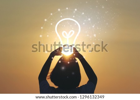 Creative idea and innovation concept, Woman hand holding light bulb on beautiful sunset background 