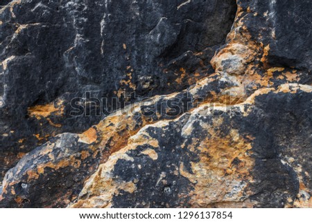 Bright stone background. Black and yellow stone textured surface of sandstone wall of (Königstein) Koenigstein Fortress. Natural rocky texture. Filled full frame picture. Concept of split, dissent.