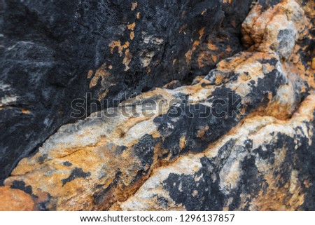 Bright stone background. Black and yellow stone textured surface of sandstone wall of (Königstein) Koenigstein Fortress. Natural rocky texture. Filled full frame picture. Concept of split, dissent.