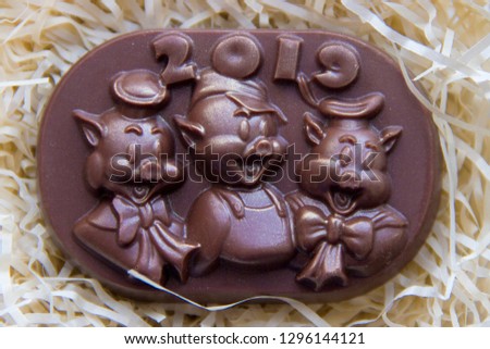 Chocolate figure with the inscription 2019 and the symbol of the year piglets. Three pigs pictured on chocolate