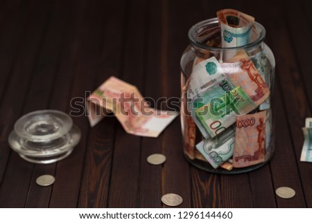 Russian banknotes in glass jar on wooden background. Saving money concept