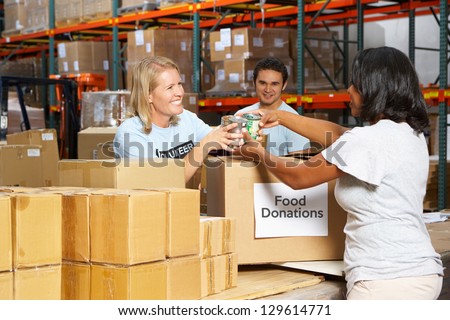 Volunteers Collecting Food Donations In Warehouse Royalty-Free Stock Photo #129614771