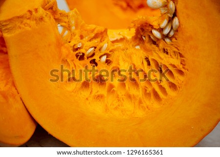 A slice of tasty and healthy vegetable - juicy bright and orange pumpkin with seeds on the table close-up.