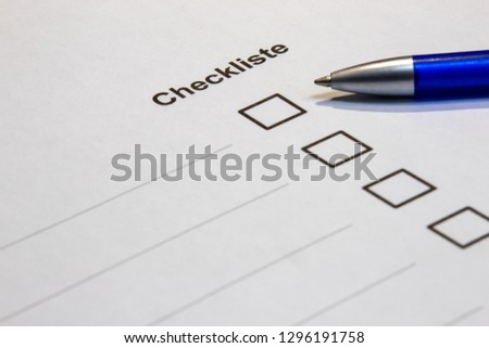 View of a checklist with word checklist in german language with selection boxes and blue pen against black background