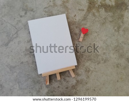White board and heart-shaped clip on gray cement background