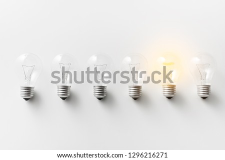 Concept for creativity, innovation and solution. Illuminated light bulb in row of dim ones on white background