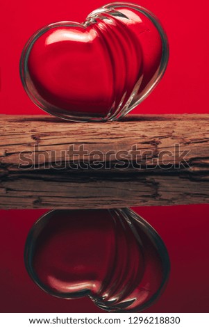 Glass red heart on an old wooden table. Beautiful red background. Valentines day.