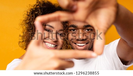Cheerful black couple posing together, framing faces with hands, panorama