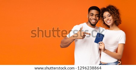 We are going to trip! Friendly african-american man and woman holding tickets and passport, orange background, panorama with copy space
