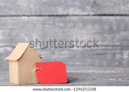 Paper house with sale tag on grey wooden table