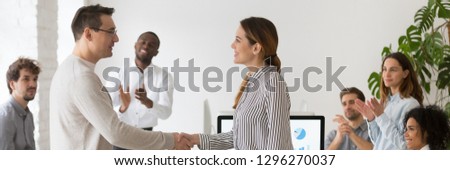 Boss handshaking with promoted female worker congratulating with success showing appreciation with good work result diverse colleagues clapping hands. Horizontal photo banner for website header design