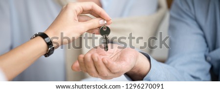 Horizontal photo reliable real estate agent giving keys to senior couple, male female hands close up, spouses buying new home receive loan mortgage investing concept, banner for website header design