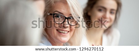 Horizontal close up photo focus aged attractive businesswoman boss in glasses listen colleague ideas information at briefing meeting negotiation with business partners banner for website header design