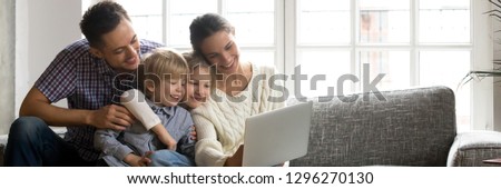 Parents little kids sitting on couch using computer watching video, family enjoy time together, buying online modern tech easy usage concept, banner for website header design with copy space for text