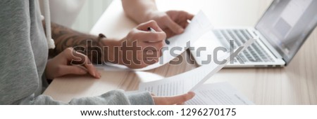Close up wife husband hands, couple sitting at desk hold papers reading document received letter from bank use pc online banking, check planning family budget concept, banner for website header design