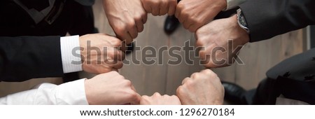 Top above close up view group of businessmen in formal suits standing putting hands fists in circle shape. Teamwork trust motivation support concept, horizontal photo banner for website header design