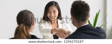 Smiling successful young asian applicant handshake with hr manager feels happy getting hired, boss congratulating employee new job employment concept. Horizontal photo banner for website header design Royalty-Free Stock Photo #1296270187