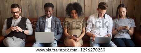 Multi-ethnic businesspeople sitting in row on couch absorbed in mobile phones computers girls guys addicted in gadgets devices. Overuse dependence on internet concept, banner for website header design