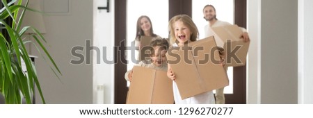 Horizontal photo happy family couple little children hold boxes belongings running into new house buying first home loan and mortgage concept. Banner for website header design with copy space for text