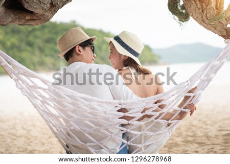 Asian couple is sitting and kissing at sunset tropical beach on Valentine's Day