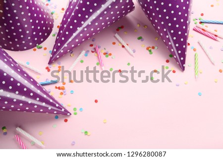 Birthday paper caps with candles and confetti on pink background