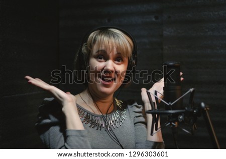 Shoked woman a singer in a headphones in a sound recording studio room..