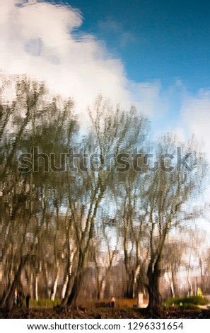 Blurry nature, park trees and sky with clouds reflected in river waters