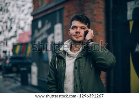 A man talking on the phone against the backdrop of the cityscape. Young businessman communicates by cell phone in industrial landscape