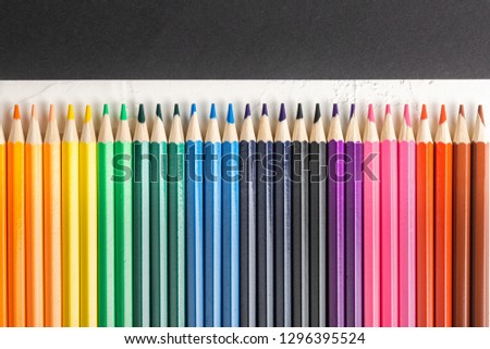 colored pencils in row on a black background top view. Art set of pencils for schoolboy with free space. view from above