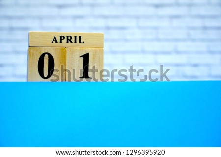 April 1st. Wood block calendar on blue table, white brick wall background. Spring day, Free space for any text design. All Fool's Day.