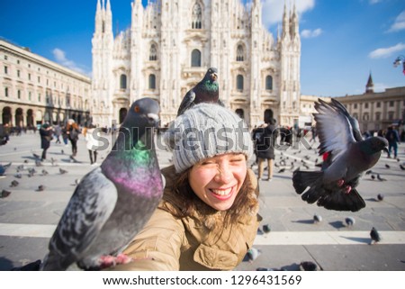 Travel, holidays and winter vacations concept - Happy young woman take selfie photo with funny pigeons in front of Duomo Milan Cathedral