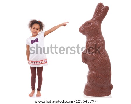 African Asian girl pointing a giant chocolate rabbit, isolated on white background