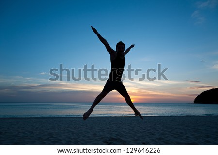 Happy man jumping on the beach on the background of sea