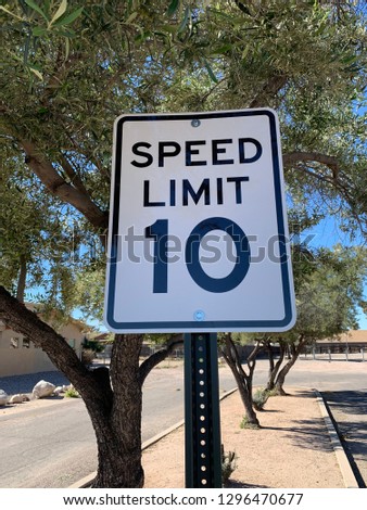 Speed Limit 10 Miles Per Hour sign in desert with trees in background
