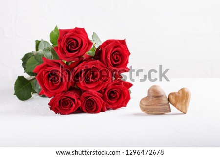 Bouquet of red roses and two wooden hearts on a white table. Copy space. Happy Valentines day, greeting card.  