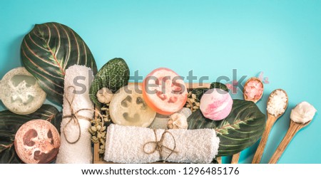 Organic Spa cosmetics, composition with soap and Spa care items on blue background with tropical leaf, Spa and body care concept