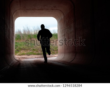 man running through dark tunnel escaping Royalty-Free Stock Photo #1296518284
