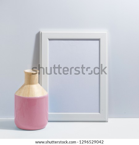 Mock up white frame and pink vase on book shelf or desk. Minimalistic concept.
