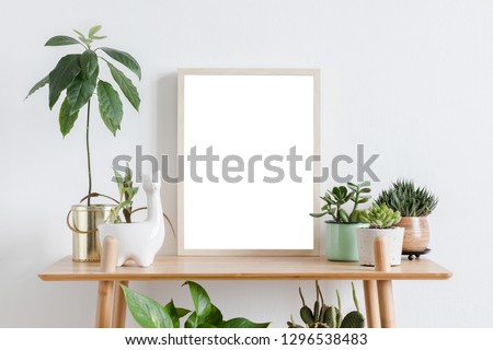 Stylish room interior with mock up photo frame on the brown bamboo shelf with beautiful plants in differents hipster and design pots. White walls. Modern and floral concept of shelfs.