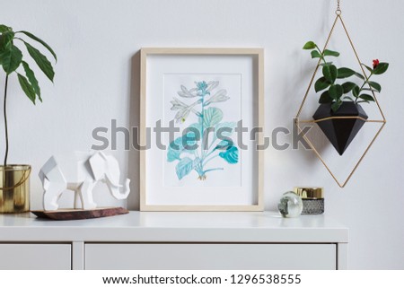 Modern and stylish home interior, floral poster mock up with wooden photo frame, avocado plant, elephant figure and hanging plant in geometric pot on white wall background. Concept of white shelf.