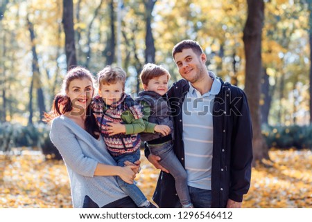 Natural pictures of a happy family of four having fun outsiade on a sunny autumn day. Togetherness and happiness concept