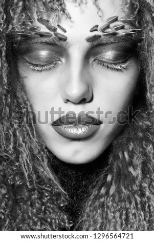Closeup portrait of one beautiful wild young woman with bright golden animal monkey makeup with thorns on face in fur violet wig in studio, vertical picture
