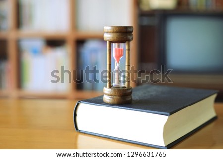 Close-up pictures of the hourglass on books in the library bookshelf in the background selective focus and shallow depth of field