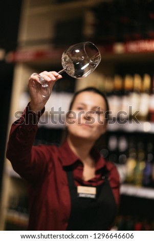 Picture of woman with wine glass on blurred background of shelves with bottles