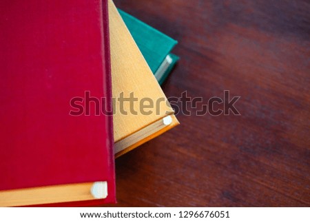 old large books with red, yellow and green covers are on a wooden table, flat lay