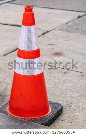 bright orange and white reflective safety cone on the sidewalk with copy space