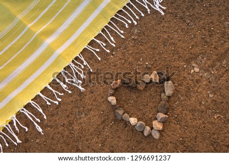 Valentine’s day concept Heart of stones on she beach with a beach towel green Couple celebrating valentine’s day near the sea. Icon of love Love is beautiful and forever Lovely holiday landscape  